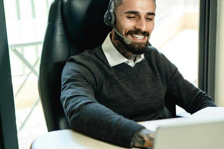 Smiling customer service representative using a headset in a modern office setting.